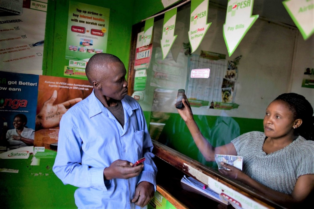 Women behind screen showing mobile to customer