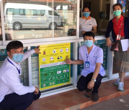 Image of two ministry of health in front of COVID-19 communications poster